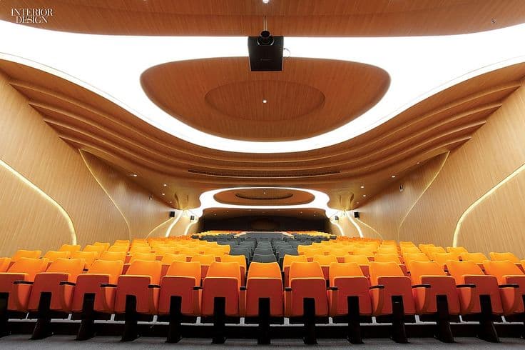 An auditorium with curved timber walls and colorful seating